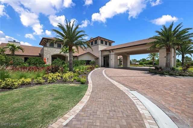 mediterranean / spanish home with stone siding, a front yard, and a tiled roof