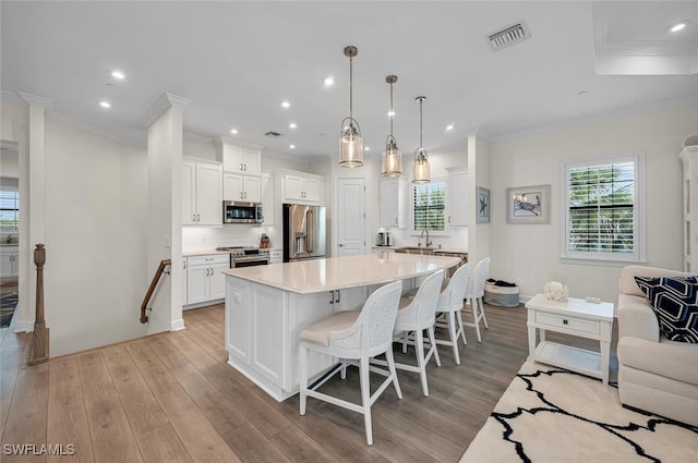 kitchen featuring visible vents, a kitchen bar, light countertops, light wood-style floors, and stainless steel appliances