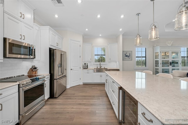 kitchen with a wealth of natural light, visible vents, a sink, stainless steel appliances, and white cabinets