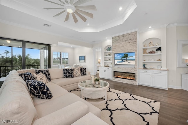 living area featuring visible vents, built in shelves, wood finished floors, crown molding, and a raised ceiling