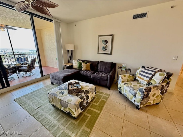 tiled living room featuring floor to ceiling windows, visible vents, and ceiling fan