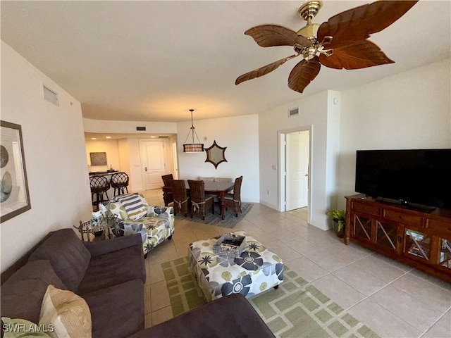 living area with light tile patterned floors, baseboards, visible vents, and a ceiling fan