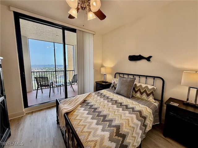 bedroom featuring ceiling fan, wood finished floors, baseboards, access to outside, and floor to ceiling windows