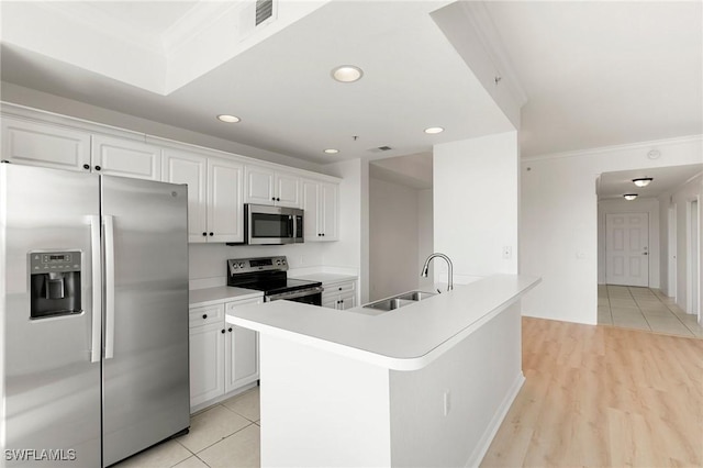 kitchen featuring recessed lighting, a sink, ornamental molding, stainless steel appliances, and white cabinets