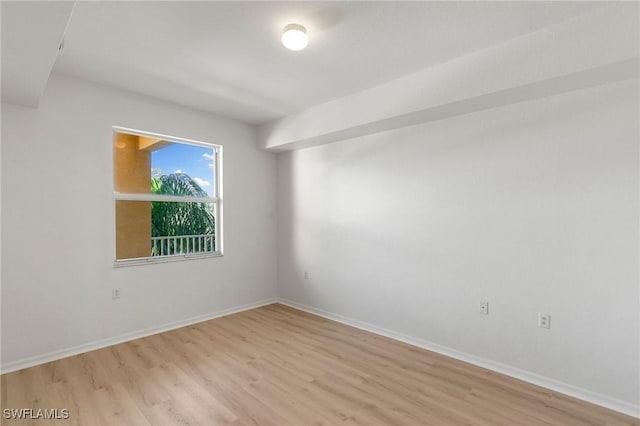 spare room featuring light wood-type flooring and baseboards