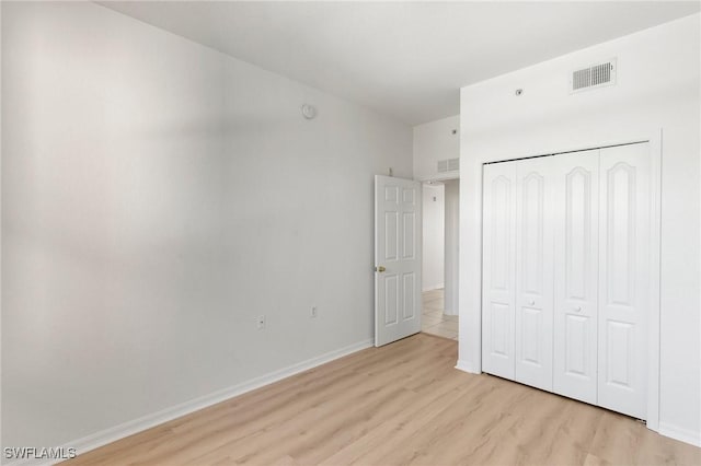 unfurnished bedroom with baseboards, visible vents, a closet, and light wood-type flooring