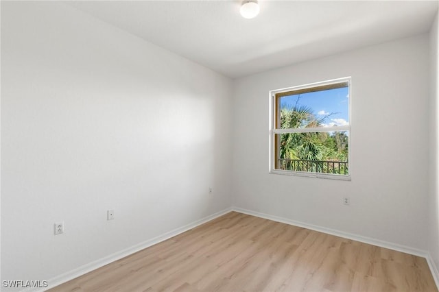 spare room with baseboards and light wood-style floors