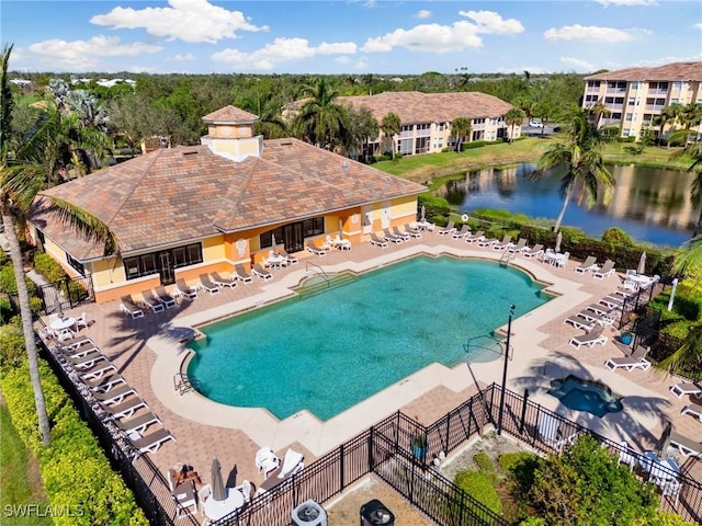 community pool featuring cooling unit, a water view, fence, and a patio area