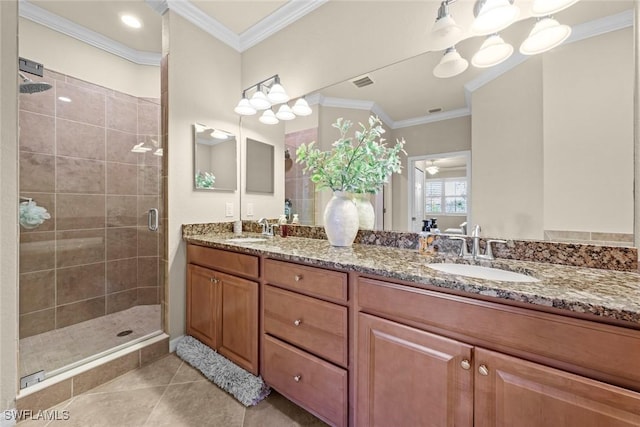 bathroom featuring tile patterned flooring, ornamental molding, a shower stall, and a sink