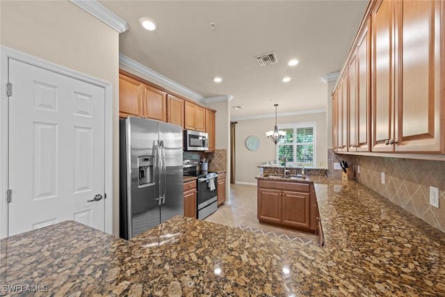 kitchen featuring visible vents, a peninsula, a sink, decorative backsplash, and appliances with stainless steel finishes