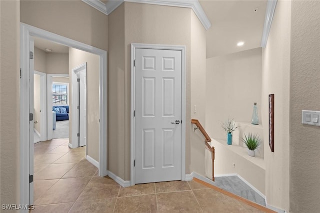 hall featuring light tile patterned floors, crown molding, and baseboards