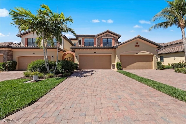 mediterranean / spanish-style home with stone siding, stucco siding, and decorative driveway