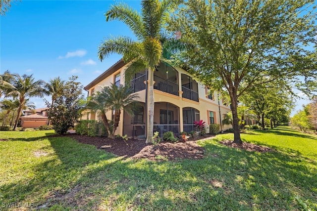 back of property featuring stucco siding, a yard, and a sunroom