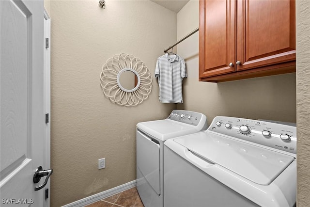 clothes washing area with baseboards, cabinet space, dark tile patterned flooring, and washing machine and dryer