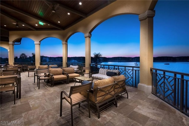 patio terrace at dusk with an outdoor hangout area and a water view