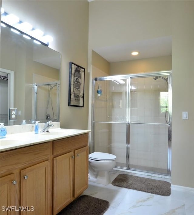 bathroom with a sink, a shower stall, double vanity, and toilet