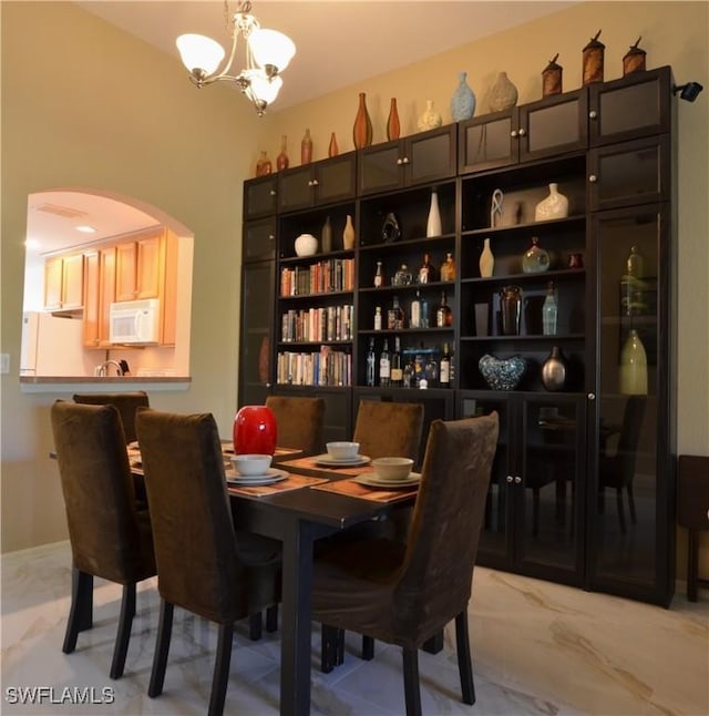 dining area featuring arched walkways and a chandelier