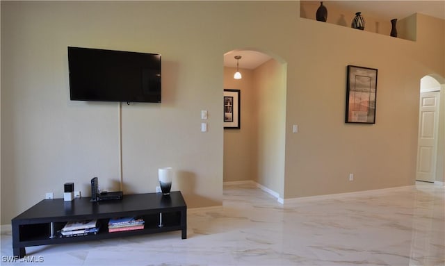 living room featuring arched walkways, marble finish floor, and baseboards