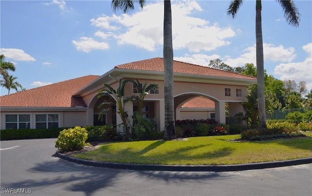 view of front of property with stucco siding, a tile roof, and a front lawn