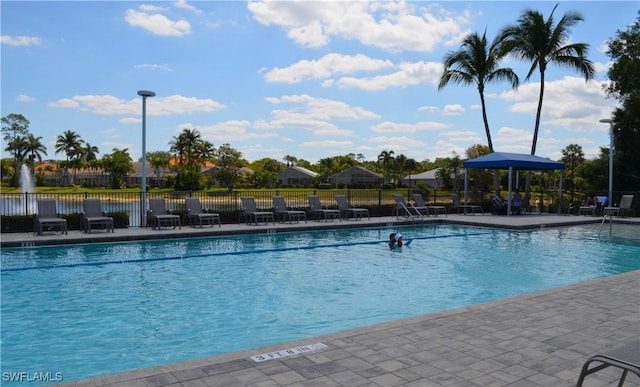 pool with a patio area and fence