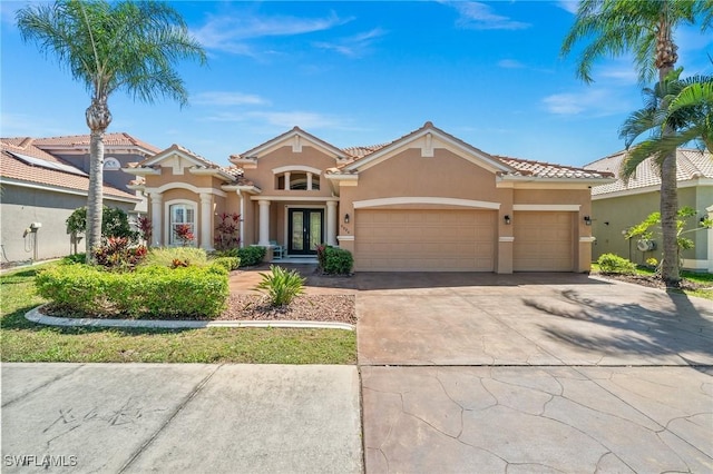 mediterranean / spanish-style home with french doors, stucco siding, concrete driveway, a garage, and a tiled roof