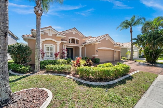 mediterranean / spanish-style home featuring a garage, a tile roof, concrete driveway, and stucco siding