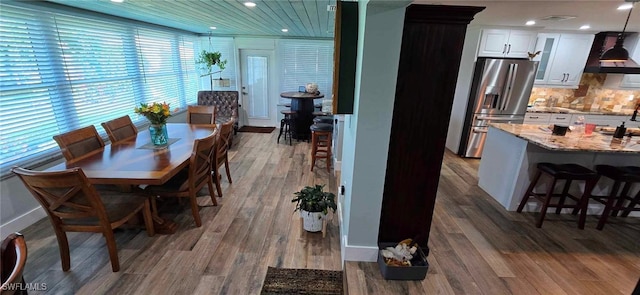 dining space with baseboards, wood finished floors, and recessed lighting