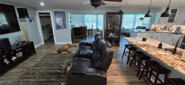 living area with dark wood-type flooring, visible vents, baseboards, and a ceiling fan