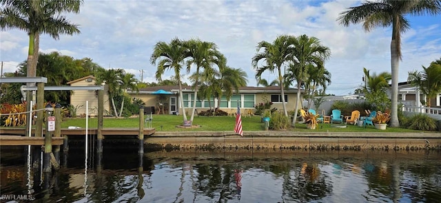 rear view of property featuring a water view and a lawn