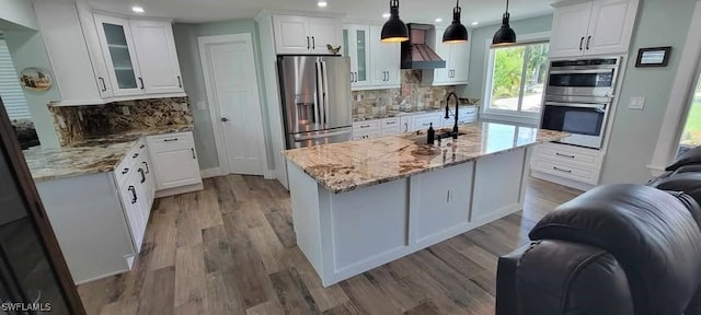 kitchen with appliances with stainless steel finishes, open floor plan, custom range hood, and wood finished floors