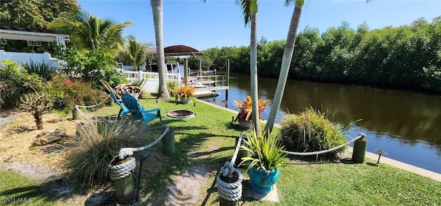 view of yard featuring a water view, an outdoor fire pit, and a dock