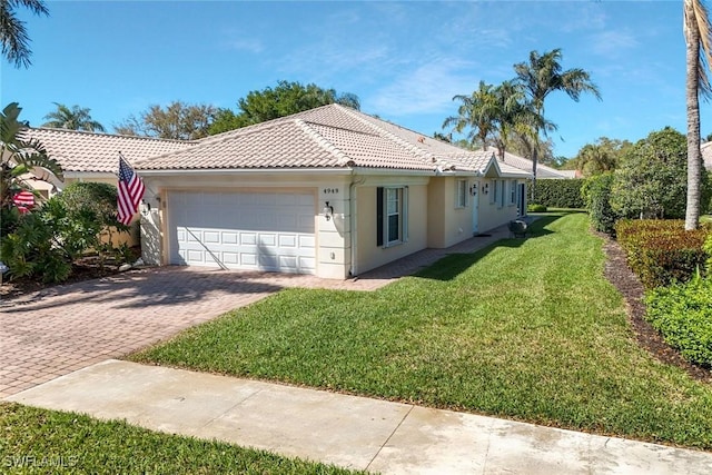 view of front of house with decorative driveway, a tile roof, stucco siding, a garage, and a front lawn