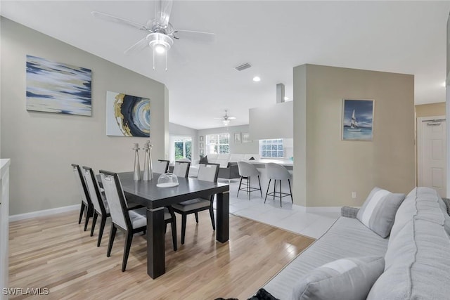 dining space featuring a ceiling fan, visible vents, vaulted ceiling, baseboards, and light wood-type flooring