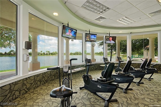 gym with a water view, carpet floors, visible vents, and a paneled ceiling