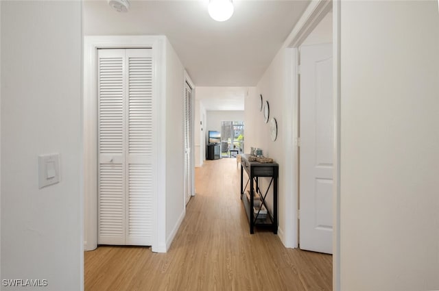 hall with light wood-type flooring and baseboards