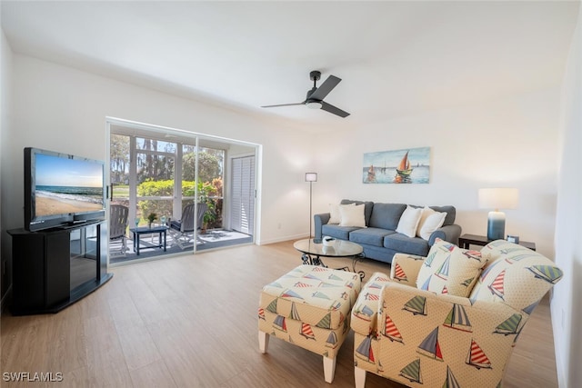 living area with baseboards, a ceiling fan, and wood finished floors