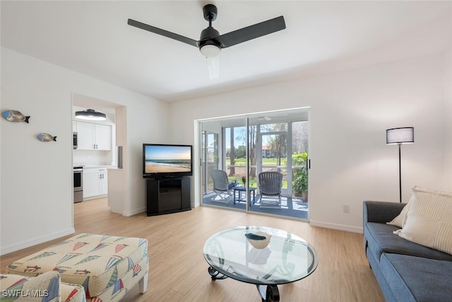 living area featuring ceiling fan, light wood-style flooring, and baseboards