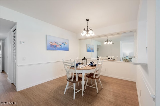 dining area with a chandelier, wood finished floors, and baseboards