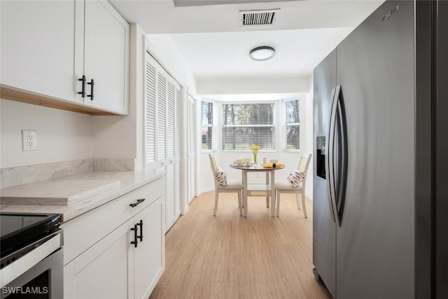 kitchen with light wood-type flooring, visible vents, stainless steel refrigerator with ice dispenser, and white cabinets