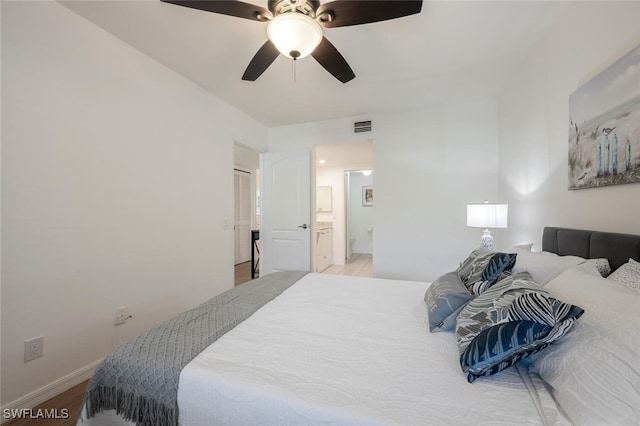 bedroom featuring visible vents, ensuite bathroom, a ceiling fan, wood finished floors, and baseboards