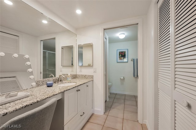 bathroom featuring toilet, vanity, a closet, a shower stall, and tile patterned floors