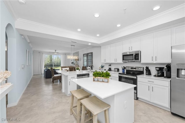 kitchen featuring a peninsula, arched walkways, ornamental molding, appliances with stainless steel finishes, and light countertops