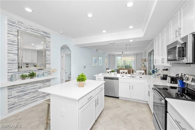 kitchen featuring arched walkways, white cabinetry, ornamental molding, appliances with stainless steel finishes, and a sink