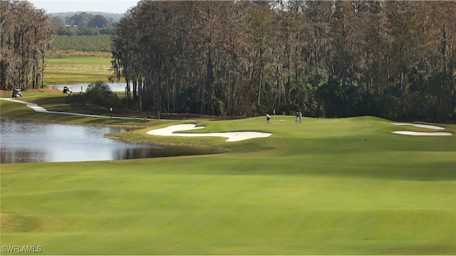 surrounding community with a lawn, view of golf course, and a water view