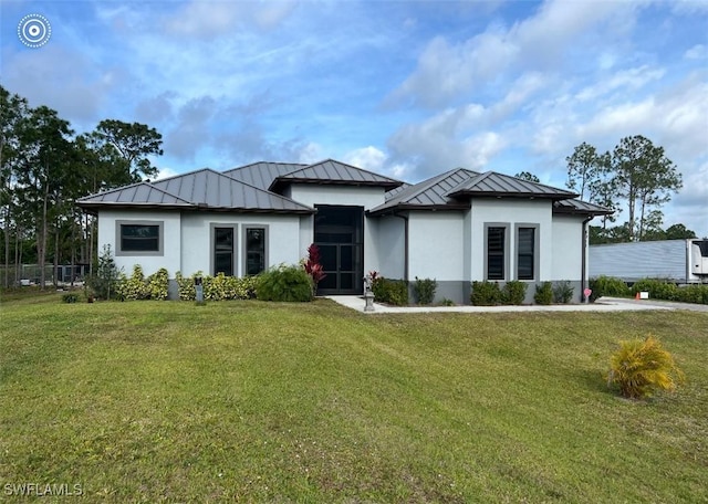 view of front of home with metal roof, a front lawn, a standing seam roof, and stucco siding