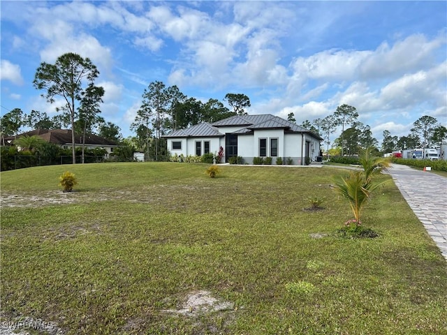 view of front of home with a standing seam roof, metal roof, and a front yard