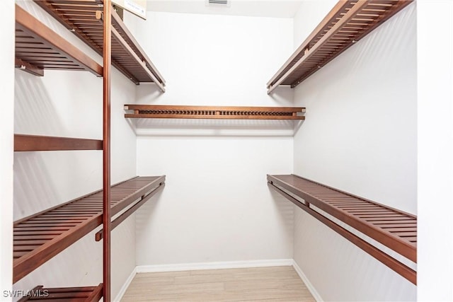 walk in closet with light wood-style floors