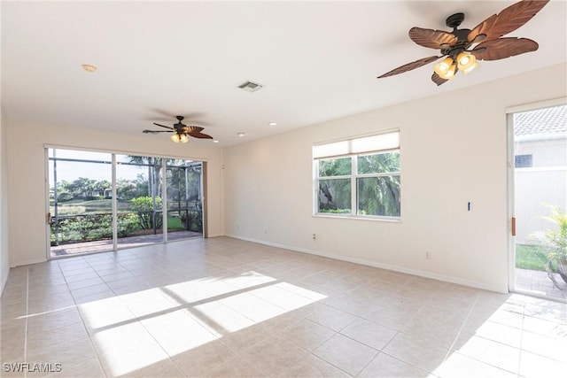 spare room featuring light tile patterned flooring, visible vents, baseboards, and a wealth of natural light