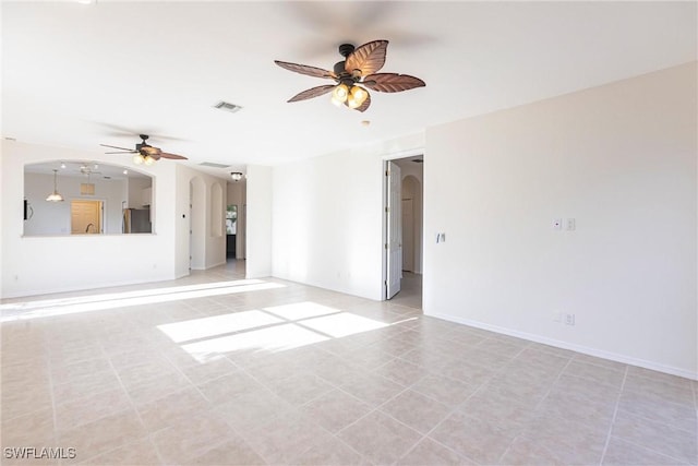 spare room featuring arched walkways, visible vents, baseboards, and a ceiling fan