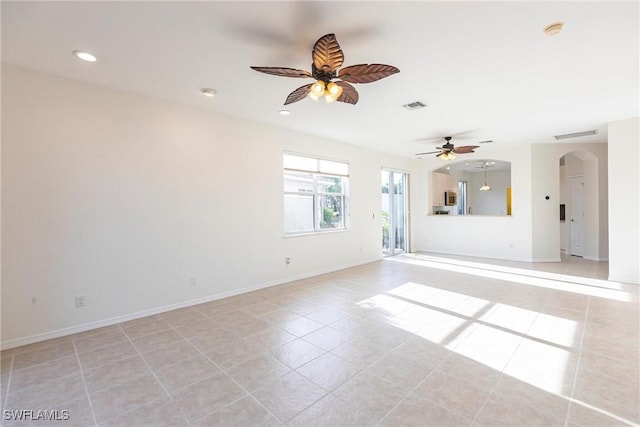 unfurnished room with light tile patterned floors, visible vents, baseboards, recessed lighting, and arched walkways